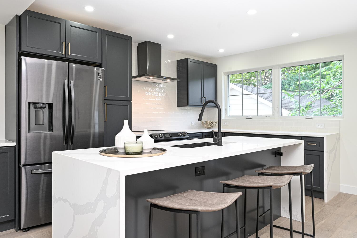 A renovated kitchen with a large island and dark cabinets