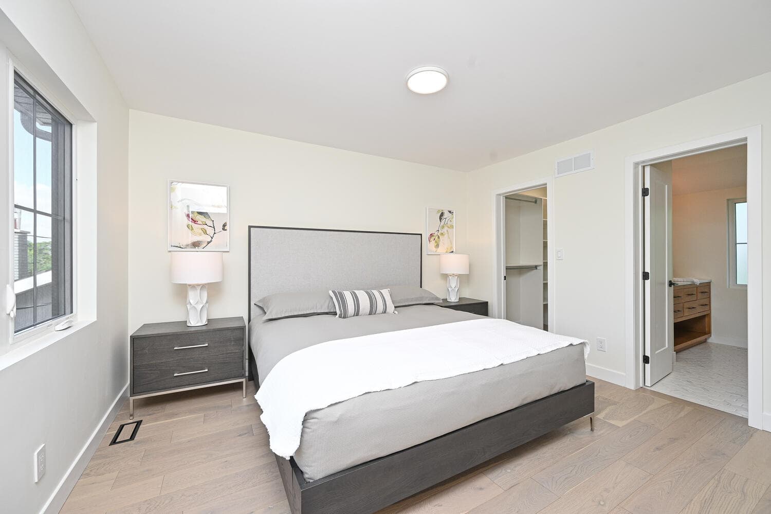 A bedroom with light oak floors and an open door to the ensuite