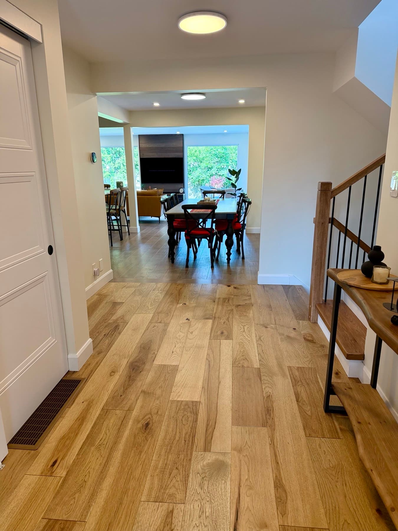 A bright front hall with a wood staircase and railing, opening onto the dining room