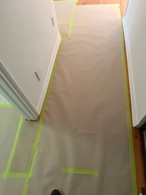 A hallway floor covered with protective paper and tape before work