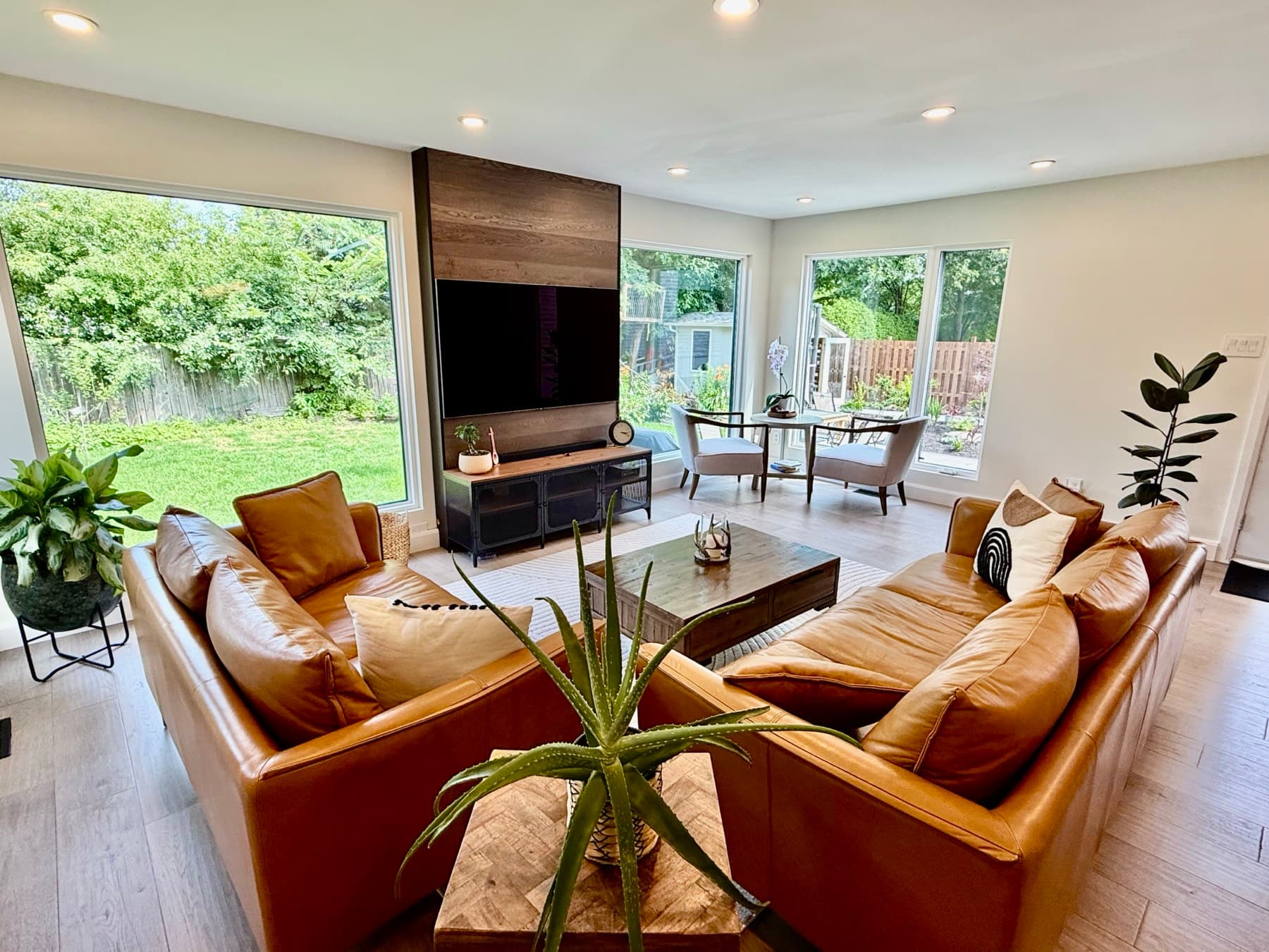 A bright living room with leather sofas and floor-to-ceiling windows onto the garden