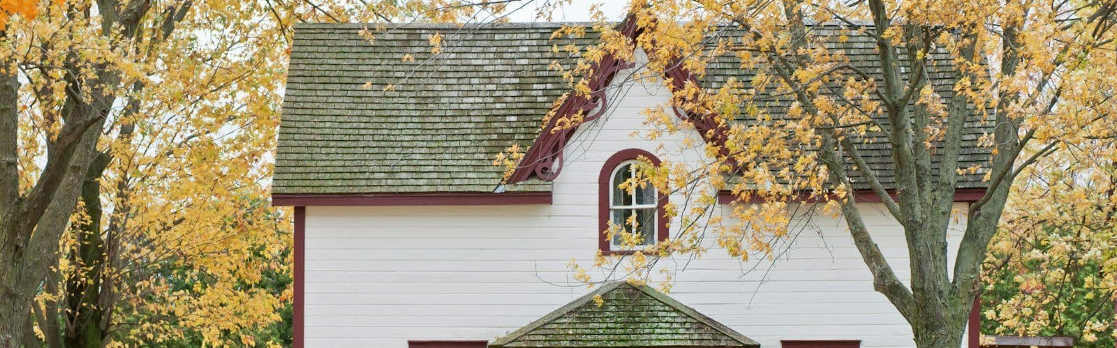 The roof and gable of a house among fall trees